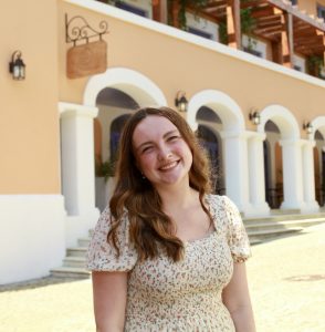 Molly smiling with her head slightly tilted in front of an ornate building