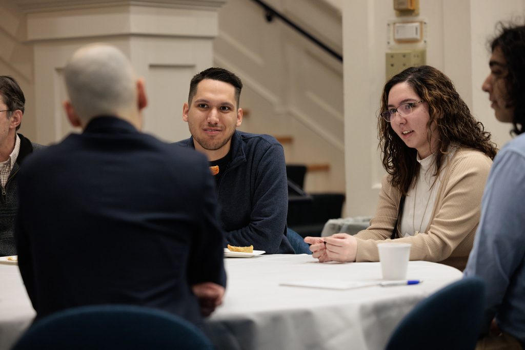 Alumni and students sit at a table during a past networking event